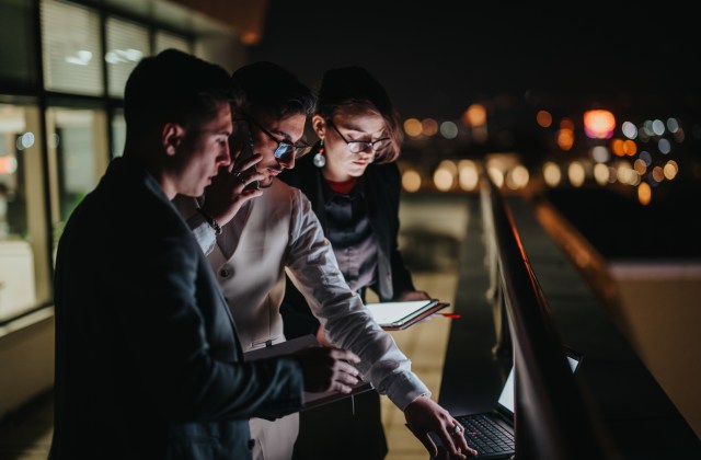 City officials collaborating at night using digital tools to analyze data and plan smart city operations.