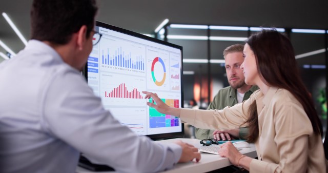 Business professionals collaborating around an analytics dashboard to share insights and make data-driven decisions securely.