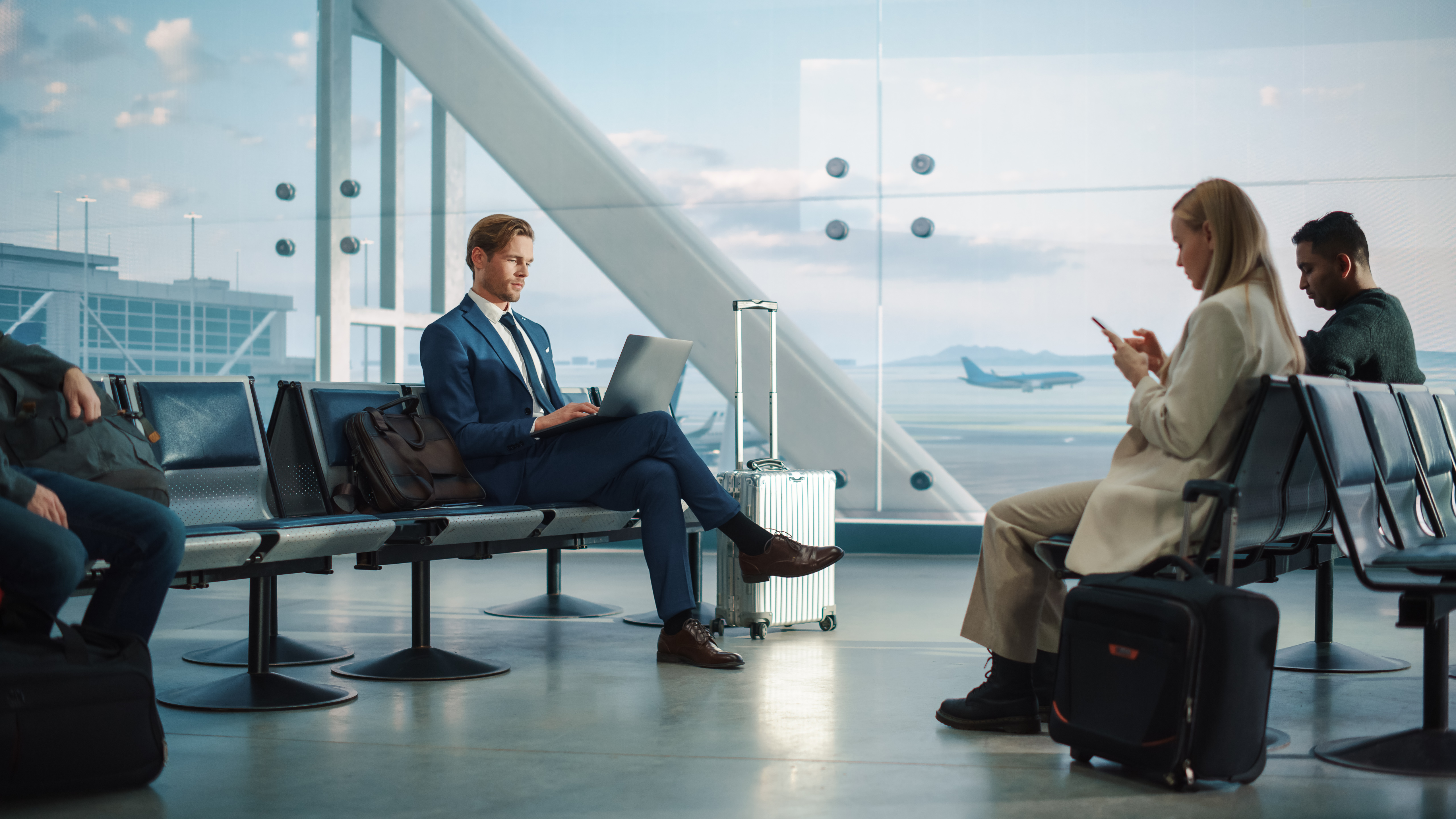 Business travelers using digital devices in an airport lounge as AI-driven tools reshape travel discovery and booking.