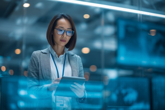 Asia/Pacific business leader reviewing AI-driven insights on a digital tablet in a modern enterprise environment.