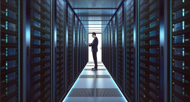 IT professional working in a datacenter aisle with server racks supporting AI and high-speed networking