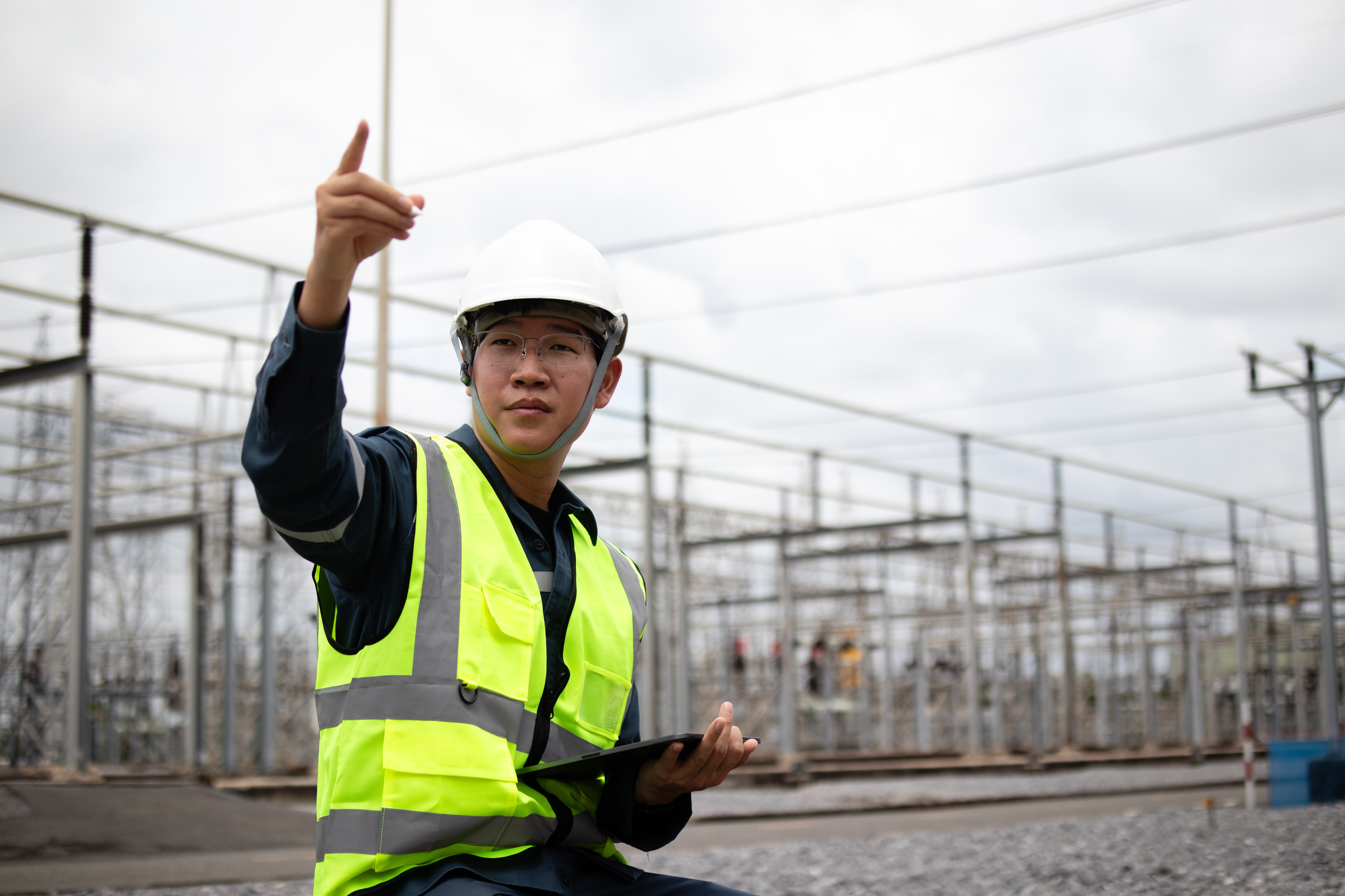 Public safety or infrastructure worker using a tablet at an energy substation, representing real-time monitoring and smart city operations