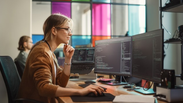 Software engineer writing code on dual monitors in a modern office environment