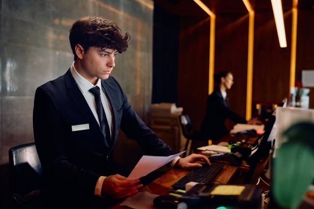 Hotel front desk staff working on desktop computer at hospitality property management system
