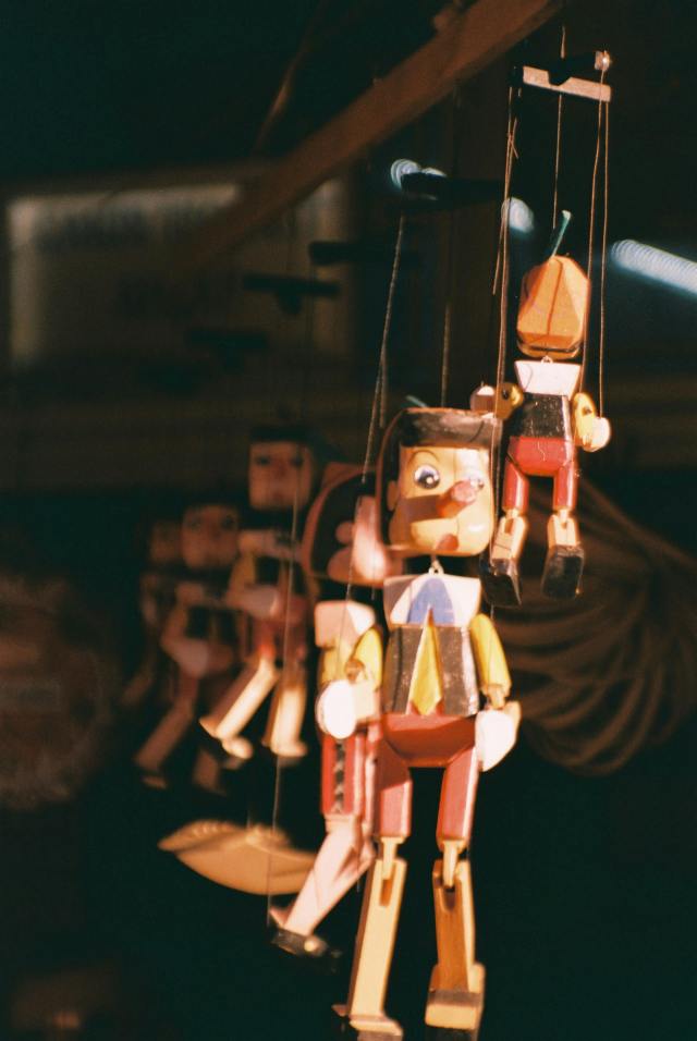 Close-up of wooden marionette puppets hanging by visible strings, representing the gap between security platform promises and architectural reality.