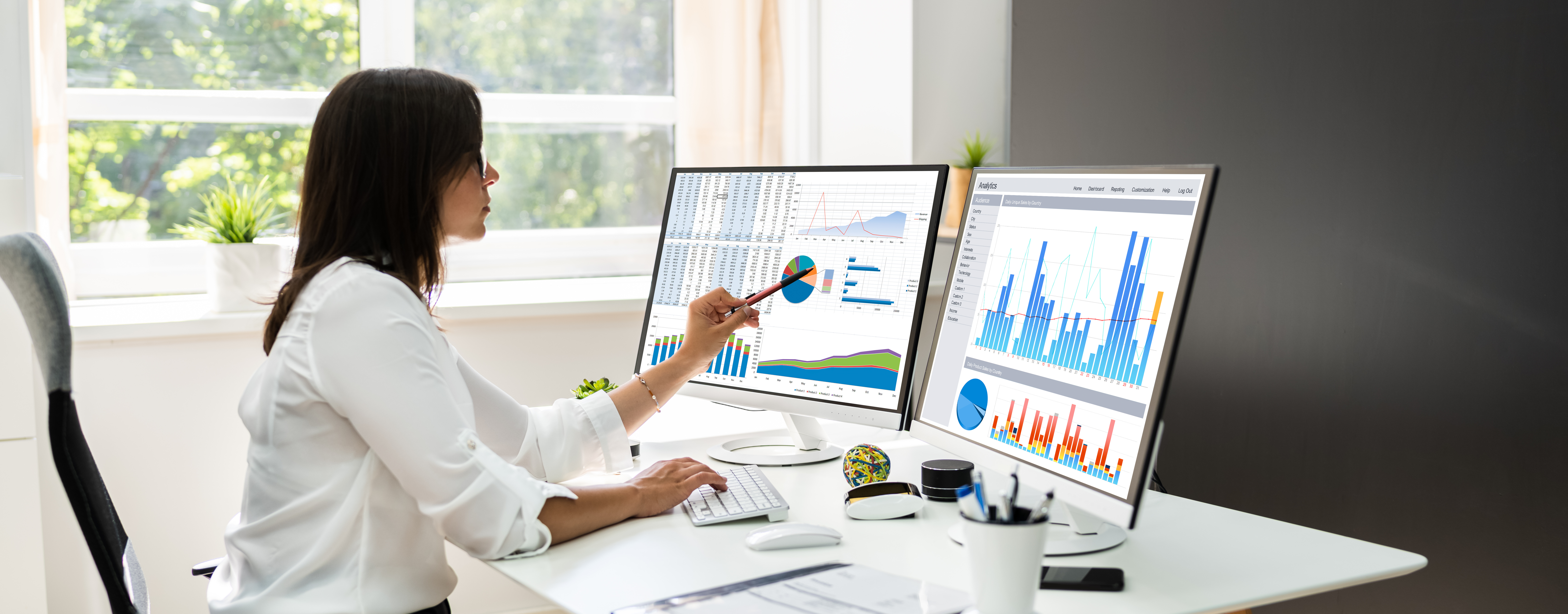 Analyst reviewing AI performance data and KPI dashboards across dual monitors