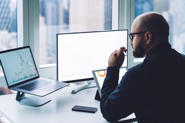 Business analyst reviewing PC market data across multiple devices including laptop, monitor, and tablet