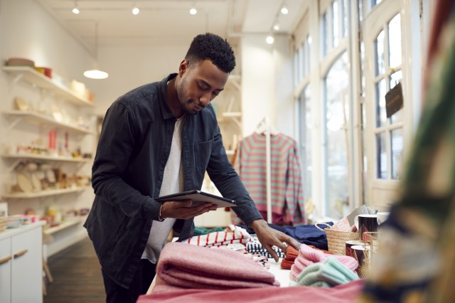 Small business owner checking retail stock with a digital tablet, representing merchants navigating agentic commerce disruption