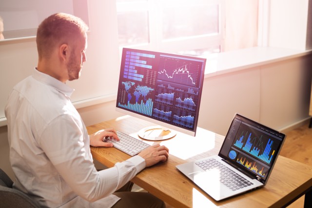 Business consultants reviewing financial and budget charts on a tablet and printed reports during a contract analysis meeting
