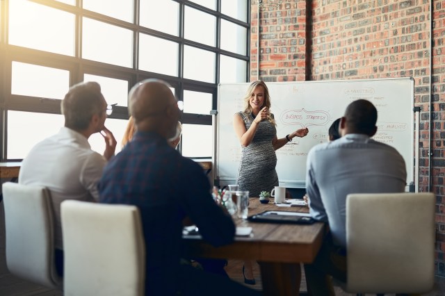 Businesswoman presenting a strategy plan on a whiteboard to colleagues in a boardroom meeting